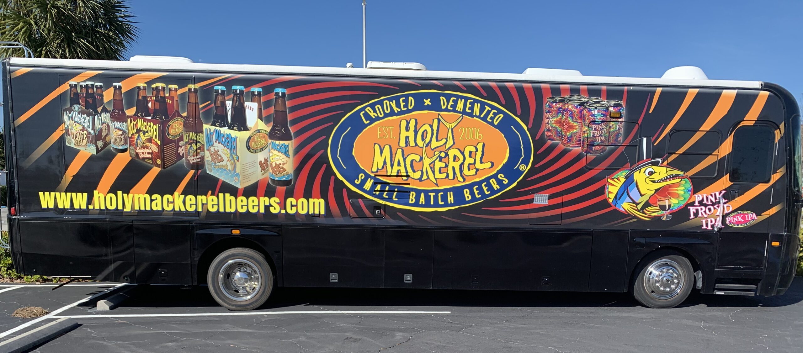 A bus with Holy Mackerel's branding parked in the shopping center located at 1414 NE 26th St, Wilton Manors, FL 33305. The bus can be seen from Wilton Drive.